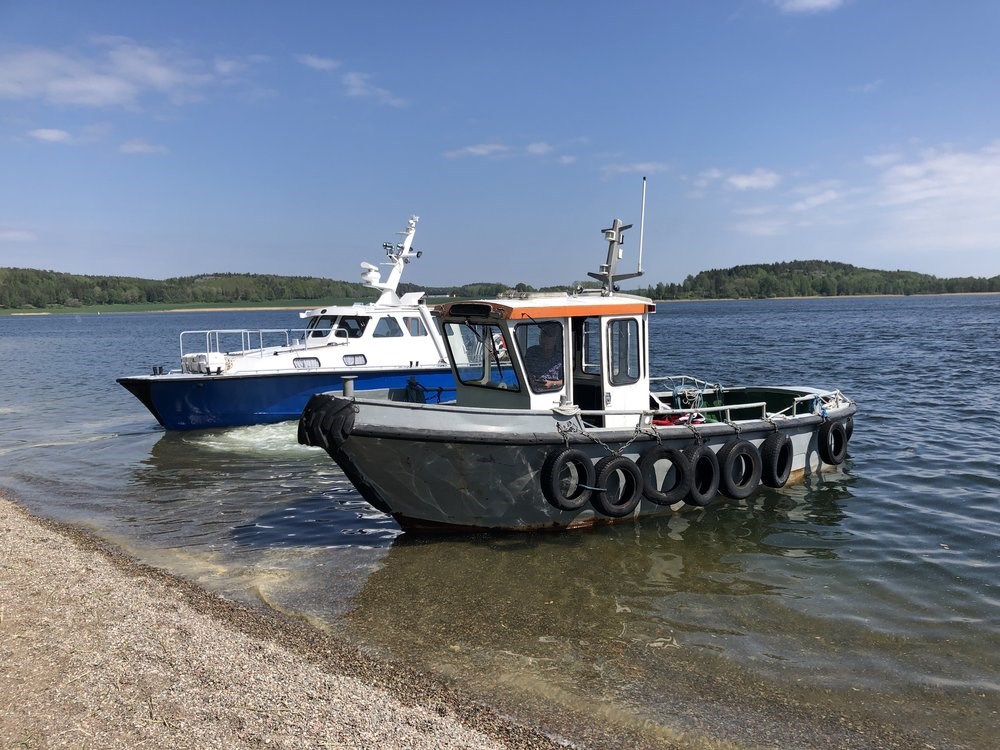 Två motorbåtar som ligger i havet bredvid en klippa